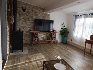 a living room with a flat screen tv on a brick wall at Maison de pêcheur in Marseillan