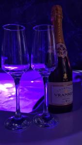 two purple wine glasses sitting next to a bottle of wine at CK Suite & Spa - Jacuzzi Privatif - Reims in Reims
