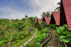 a row of houses in a garden with trees at Kelingking Terrace Cottage in Nusa Penida