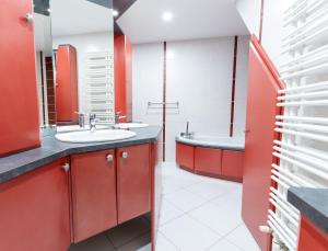 a bathroom with red cabinets and a sink and a tub at Les bulles lissoises in Lisse +17 photos