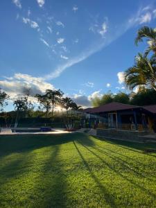a grassy yard with a house and palm trees at Hotel Campestre San Fernando in La Paloma