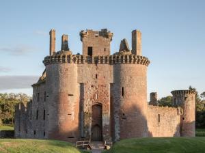 an old castle on a grassy field at Cosy wee cottage -modern, open plan, parking, EV in Glencaple