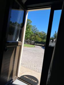 an open door with a view of a brick sidewalk at Silwerrand in Beaufort West