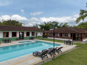 a villa with a swimming pool and patio furniture at Hotel campestre La Floresta in Armenia