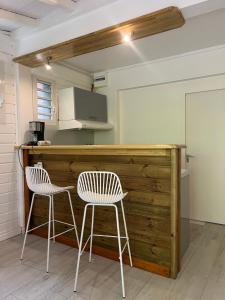 a kitchen with two white chairs and a counter at La Maison du Bonheur in Pointe-Noire