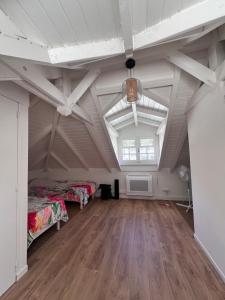 an attic room with two beds and a wooden floor at La Maison du Bonheur in Pointe-Noire