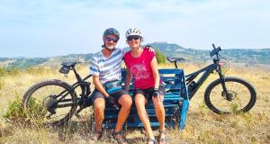 a man and a woman sitting on a bench with a bike at Residenza Menta CASA GUARNONE in Mornico Losana