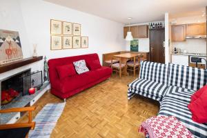 a living room with a red couch and a table at Bormio's Balcony - At the Spa in Premadio