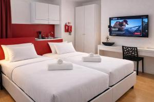 two beds in a room with a tv on the wall at Citizen Suites Asignatures by Dahlia in Sliema