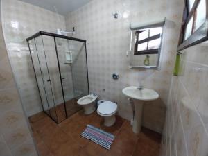 a bathroom with a shower and a toilet and a sink at Brisas da Cocanha in Caraguatatuba +19 photos