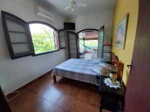 a bedroom with a bed and a table and windows at Brisas da Cocanha in Caraguatatuba