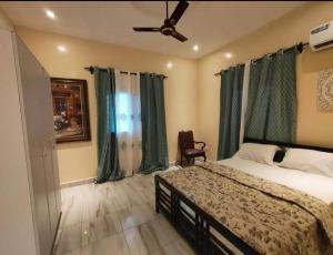 a bedroom with a bed with green curtains and a fan at Stepping Stone Apartments in Bijilo
