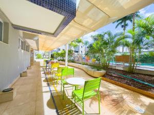 a row of green chairs and tables on a patio at Luxurious 2-Bedroom Duplex with Gourmet Balcony in Goiânia