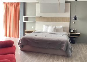 a bedroom with a large bed and a red couch at ESDUMA HK HOTEL Pachuca in Pachuca de Soto