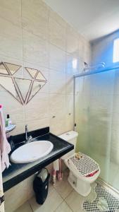 a bathroom with a sink and a shower and a toilet at Casa com piscina in Paulista