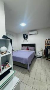 a bedroom with a bed with a purple bedspread at Casa com piscina in Paulista
