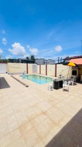 a swimming pool with two chairs and an umbrella at Casa com piscina in Paulista