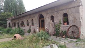 an old stone house with a wheel in front of it at Saro B&B in Tatev in Tandzatapʼ