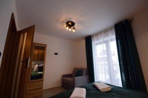 a bedroom with a bed and a window and a chair at Apartament Pod Jasieniem Jurgów in Jurgów