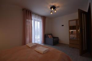 a bedroom with a bed and a chair and a window at Apartament Pod Jasieniem Jurgów in Jurgów