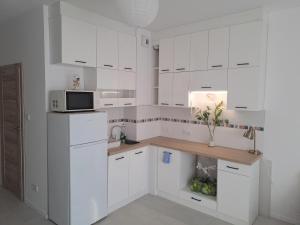 a white kitchen with a counter and a microwave at Apartament Cykady pod Warszawą in Zielonka