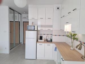 a kitchen with white cabinets and a white refrigerator at Apartament Cykady pod Warszawą in Zielonka +4 photos