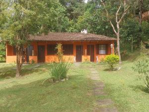 a small orange house in the middle of a yard at Chalé Refúgio na Alameda Maringá MG in Bocaina de Minas
