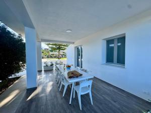 a white dining room with a white table and chairs at Al Grande Pino - Private pool, Jacuzzi and amazing Sunset in Campofelice di Roccella