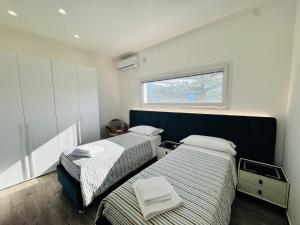 two beds in a small room with a window at Al Grande Pino - Private pool, Jacuzzi and amazing Sunset in Campofelice di Roccella +62 photos