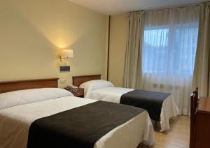 a hotel room with two beds and a window at Pensión Capital de Galicia in Santiago de Compostela