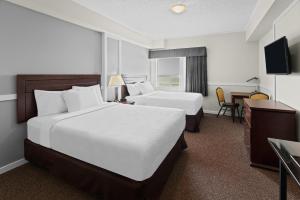 ein Hotelzimmer mit zwei Betten und einem Schreibtisch in der Unterkunft Elk Island Studios - Lamont in Lamont
