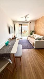 a living room with a table and a couch at Segurança e conforto na Praia Brava a 100 do mar - Condomínio Curimã in Florianópolis