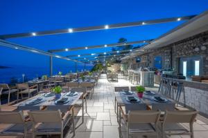 ein Restaurant mit Tischen und Stühlen und dem Meer bei Nacht in der Unterkunft Adrina Grand Hotel in Panormos Skopelos