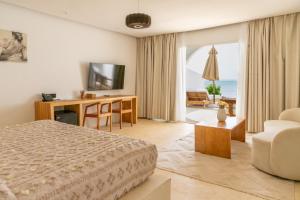 a bedroom with a bed and a desk with a television at Le Saint Tropez in Kidoti