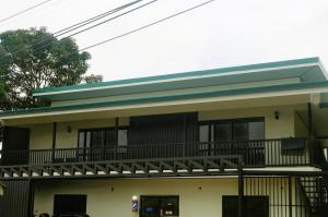 a house with a balcony and a green roof at Apartamentos Jireh in Quepos