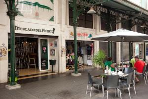 two people sitting at tables with an umbrella in front of a store at Gran Marina Suites in Las Palmas de Gran Canaria