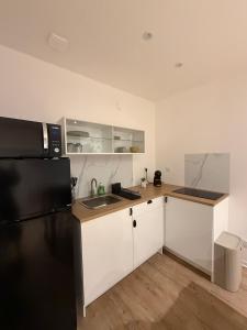 a kitchen with white cabinets and a black refrigerator at Studio moderne tout confort in Vierzon