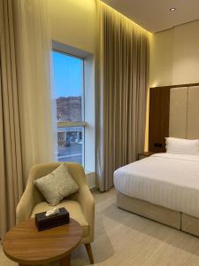 a hotel room with a bed and a chair and a table at شقق نيفا المخدومة in Hail