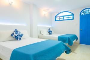 a bedroom with two beds and a blue door at Casa Caribe Colonial in Barranquilla
