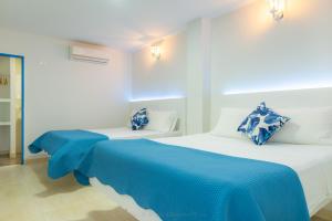 two beds in a white room with blue sheets at Casa Caribe Colonial in Barranquilla