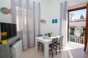a white dining room with a white table and chairs at Amalfi mia - city center in Amalfi