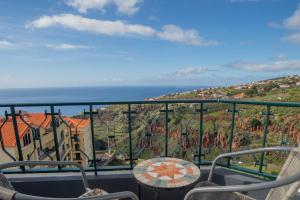 ein Balkon mit Tisch und Stühlen und dem Meer in der Unterkunft Sunset Star with Sea View in Calheta