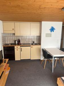 a kitchen with white cabinets and a table and chairs at Ferienwohnung Inauen in Appenzell