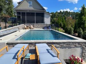 a swimming pool with two chaise lounges and a house at Lake Oconee Waterfront Apartment in Greensboro