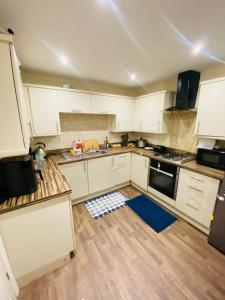 a kitchen with white cabinets and a blue rug on the floor at Stay with H&S in Kirk Sandall