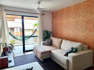a living room with a couch and a brick wall at Segurança e conforto na Praia Brava a 100 do mar - Condomínio Curimã in Florianópolis