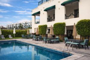 a hotel with a pool and tables and umbrellas at Depa Penthouse en Juriquilla con terraza y alberca climatizada in Juriquilla