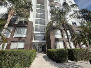 a tall building with palm trees in front of it at Depa Penthouse en Juriquilla con terraza y alberca climatizada in Juriquilla