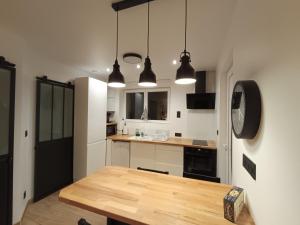 a kitchen with a wooden table and two pendant lights at Chez Mat's & Lou in Rocheville +7 photos