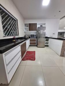 a large kitchen with a refrigerator and a red rug at Casa com Piscina px Av Holandeses a 2km da Praia Araçagy in São Luís